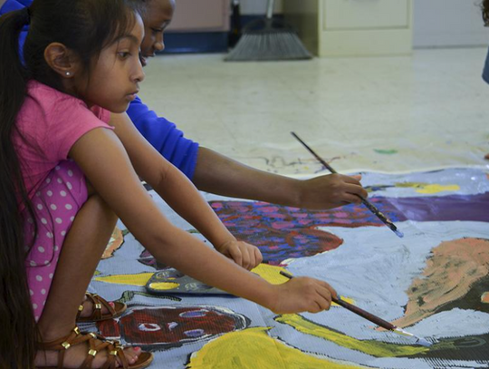 Marina Paloma and Arie Taylor Flint work together to finish the river water behind the mermaids.