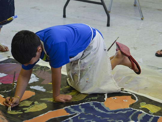 Arshaun Fallahi paints in some turtles after finishing up his merman for the mural.