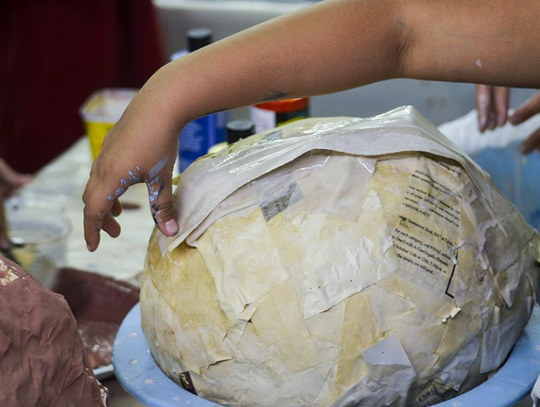 A closer view of the papier-mâché puppet head before facial features are recognizable.