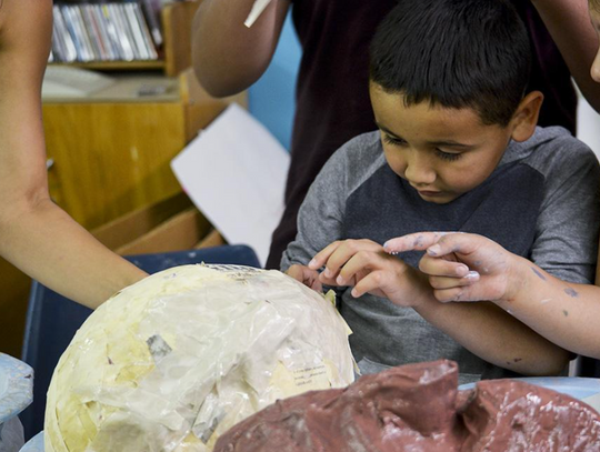 Abiel Montelongo carefully pulls the popped balloon out of the papier-mâché mermaid head.