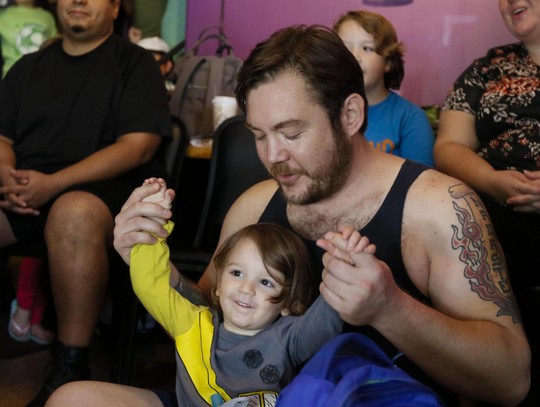 Joel Ausanka olds his son Jacob's hands as they dance together while singing "Old Macdonald Had A Farm".