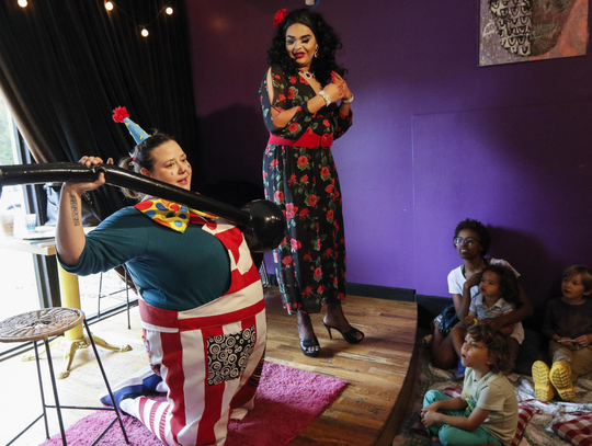 Clown and musical entertainer Molly J. Hayes demonstrates her immense strengh by lifting an inflatable barbell on stage for her audience.