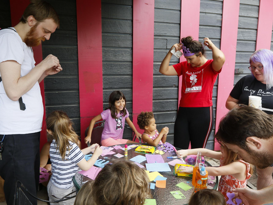 With parents leading a helping hand, story time attendees make a decorate their own crowns before attending a dance party at the end of Drag Queen Story Hour.