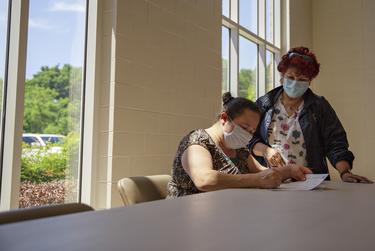 Onelia Orellana is assisted by Texas Department of State Health Services Specialist and Translator Maria Palacio as she fills out the forms needed to receive a COVID-19 vaccine at the Tennison Memorial United Methodist Church in Mt. Pleasant on May 7, 2021.